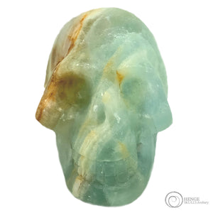 Small light blue crystal human skull head with orange and white stripe running through the skull
