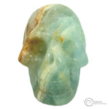 Small light blue crystal human skull head with orange and white stripe running through the skull